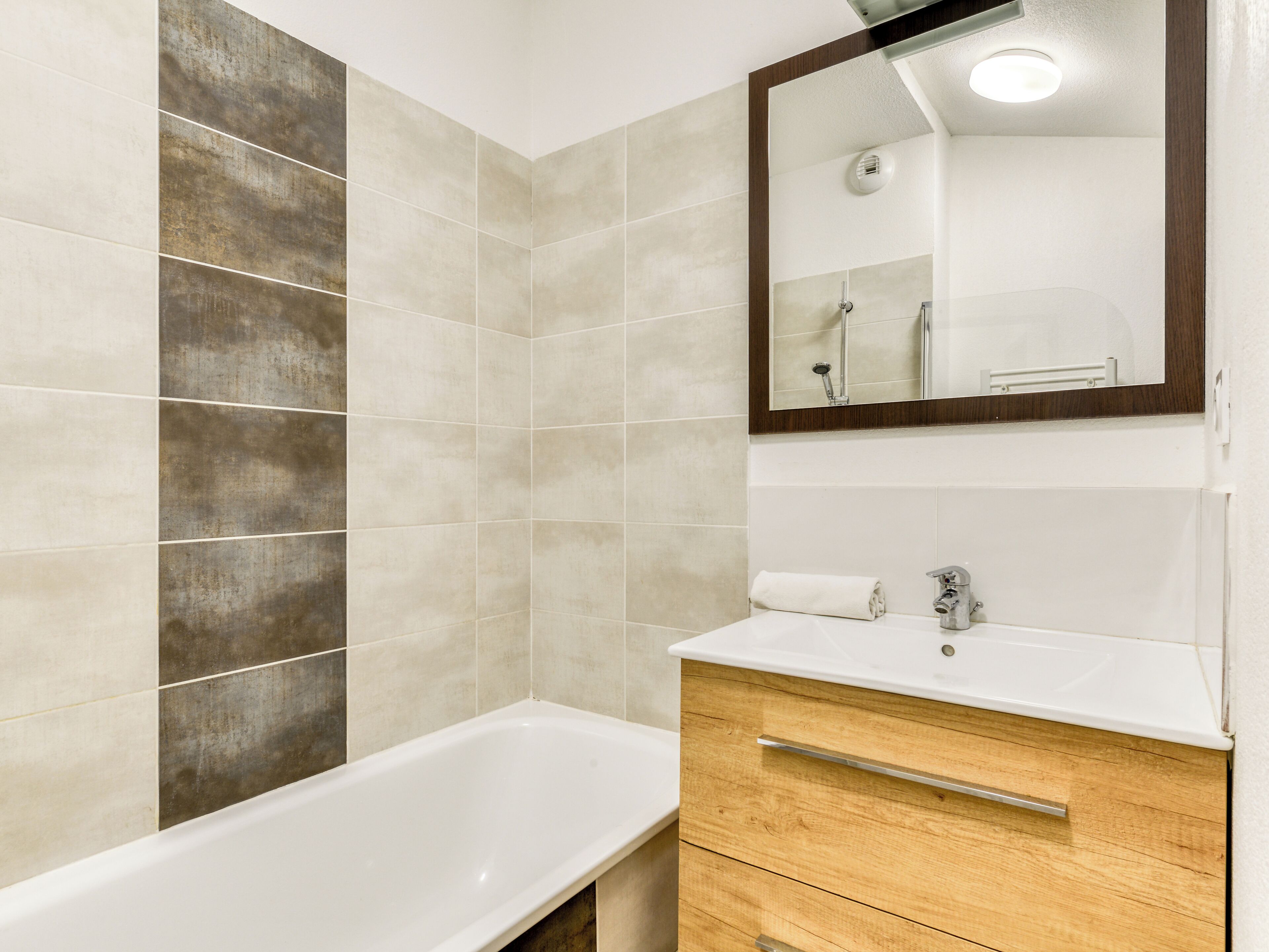 Un baño con bañera, tocador de madera y espejo.
