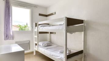A bunk bed room with a window, a radiator, and a desk.
