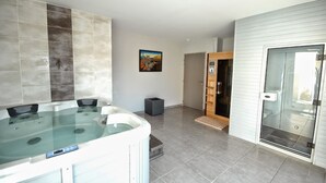 Une salle de bain moderne dotée d’une grande baignoire, d’un espace douche et de toilettes séparées par une paroi en verre.