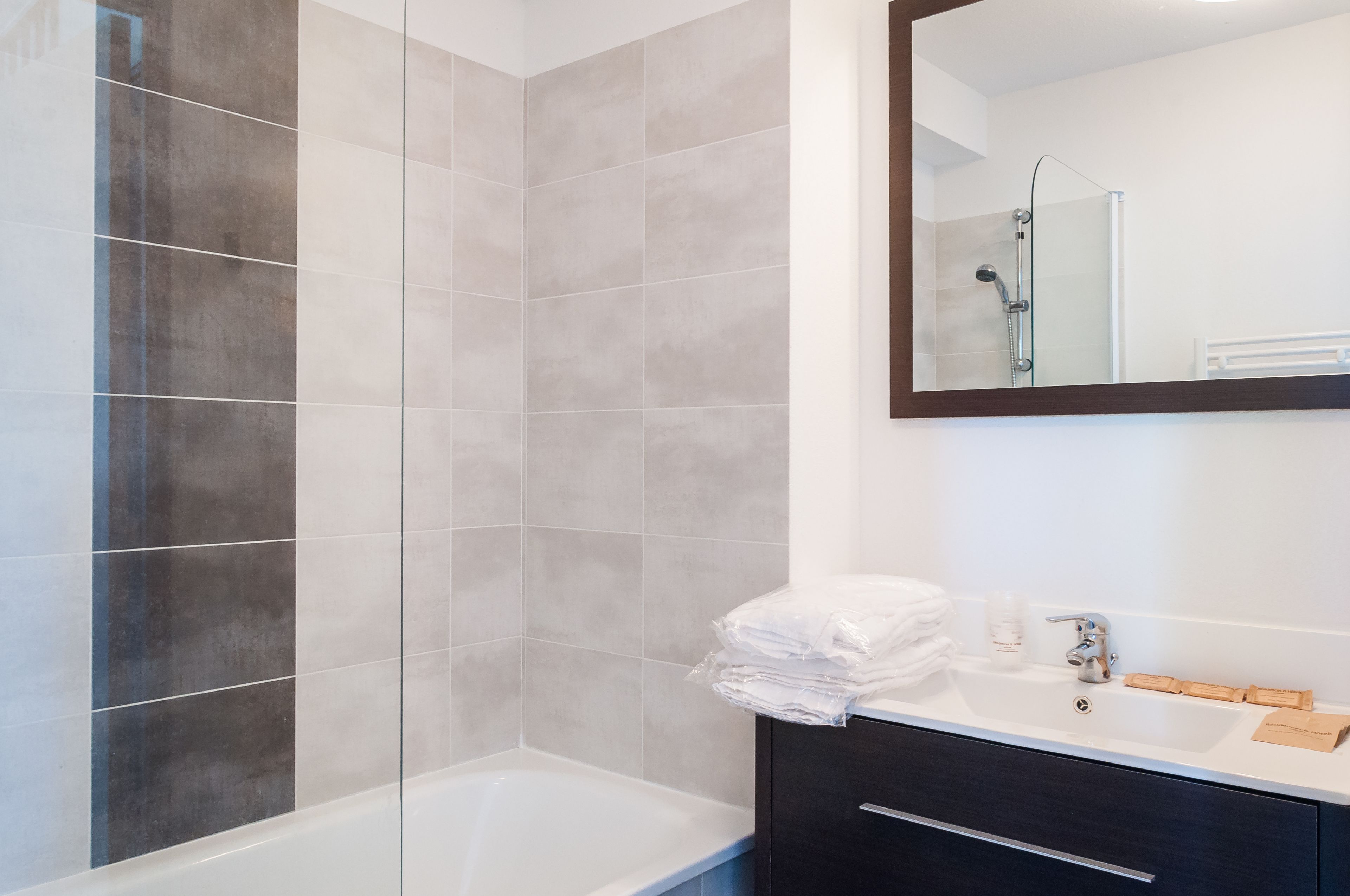 Un baño moderno con bañera, ducha y tocador con espejo.