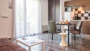Une cuisine moderne équipée d’un four à micro-ondes, d’une machine à café et d’un crédence à carreaux. On y trouve un coin repas avec une table et des chaises, ainsi qu’un canapé dans l’espace salon.