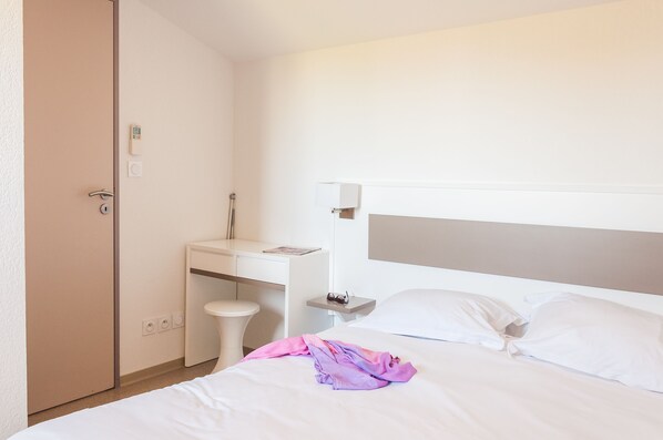 Une chambre d’hôtel avec un lit, un bureau et une armoire.
