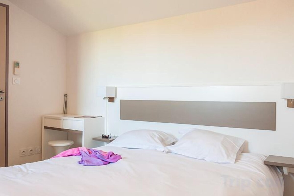 Une chambre d’hôtel comprenant un lit, une table de chevet et un bureau avec une chaise.