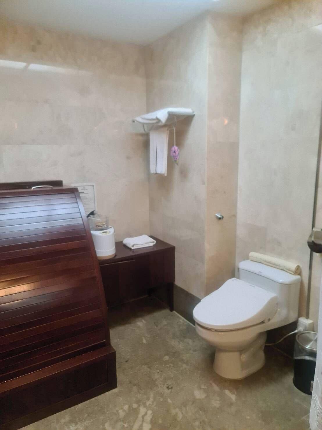 A bathroom with a wooden vanity, a toilet, and a shower area.