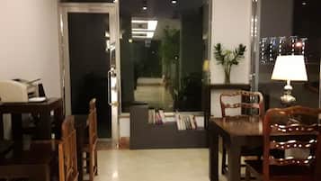 Une pièce comprenant une table à manger et des chaises, une lampe et une bibliothèque remplie de livres.