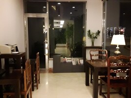 Una habitación con una mesa de comedor, sillas, una lámpara y una estantería llena de libros.