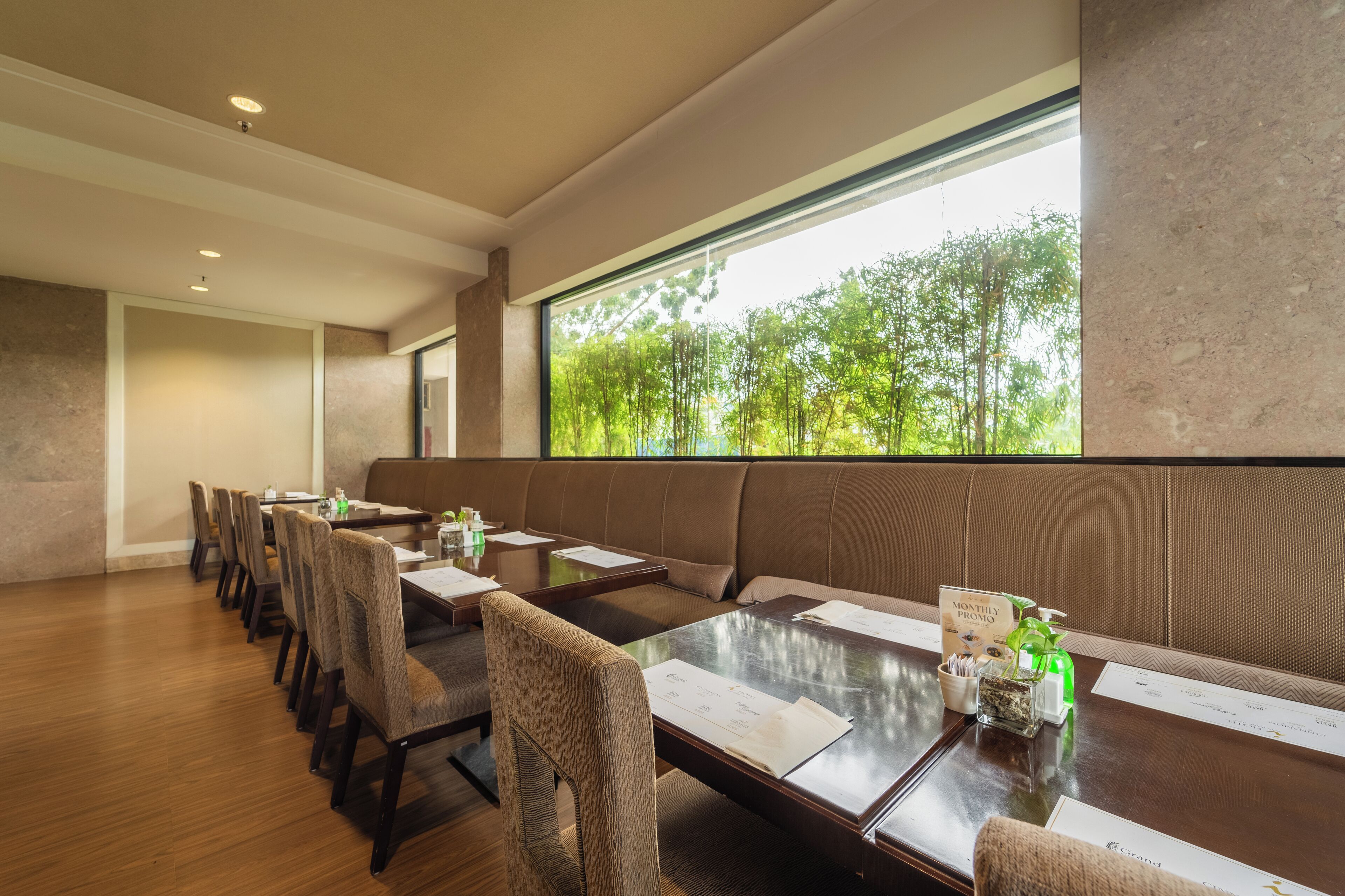 A conference room with a long table, chairs, and a large window with a view of trees.