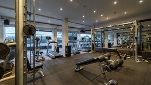 Ein Fitnessstudio mit Laufbändern, Kraftgeräten und einem Spiegel.