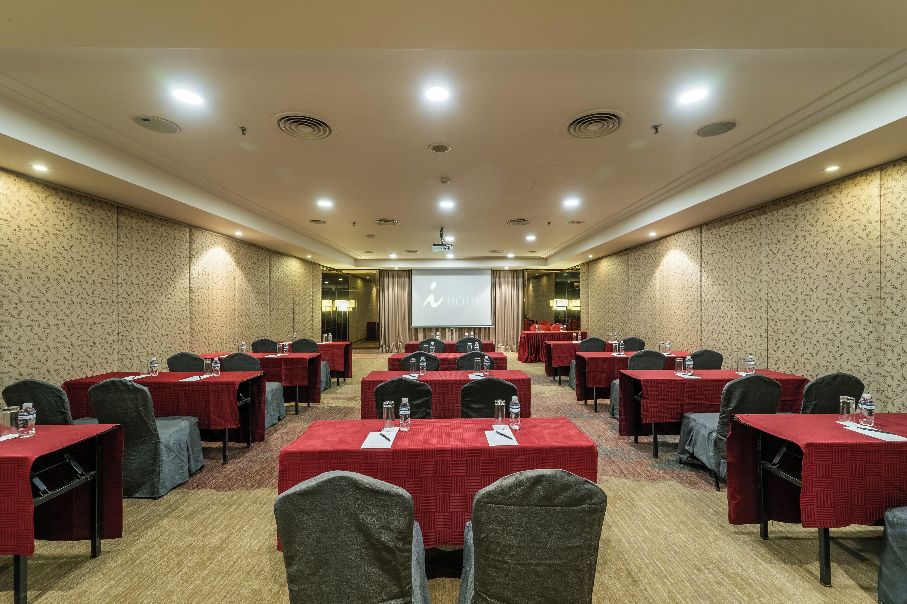 Une salle de conférence équipée de plusieurs tables, de chaises et d’un écran de projection.
