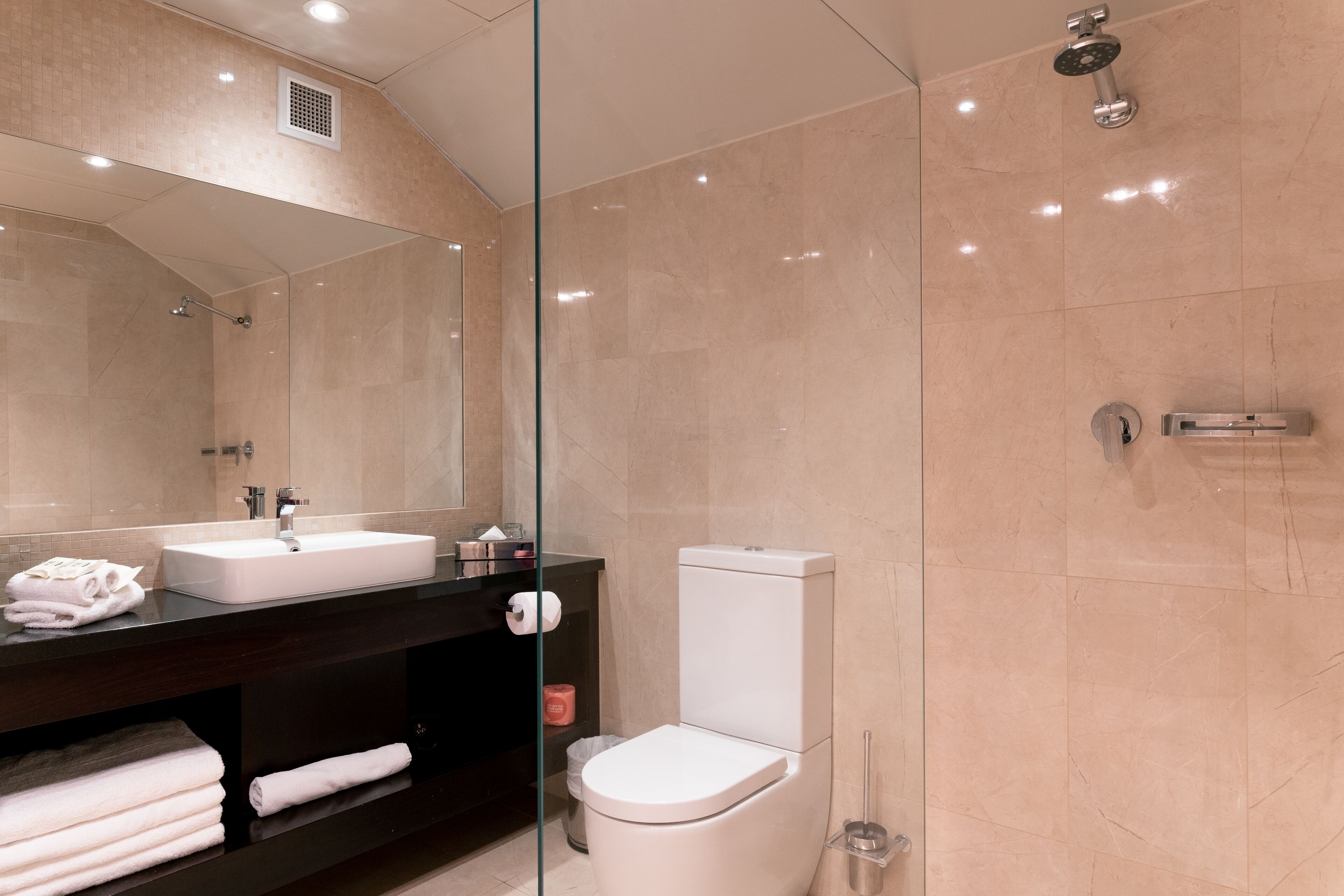 A modern bathroom with a glass-enclosed shower, a white sink, and a toilet.