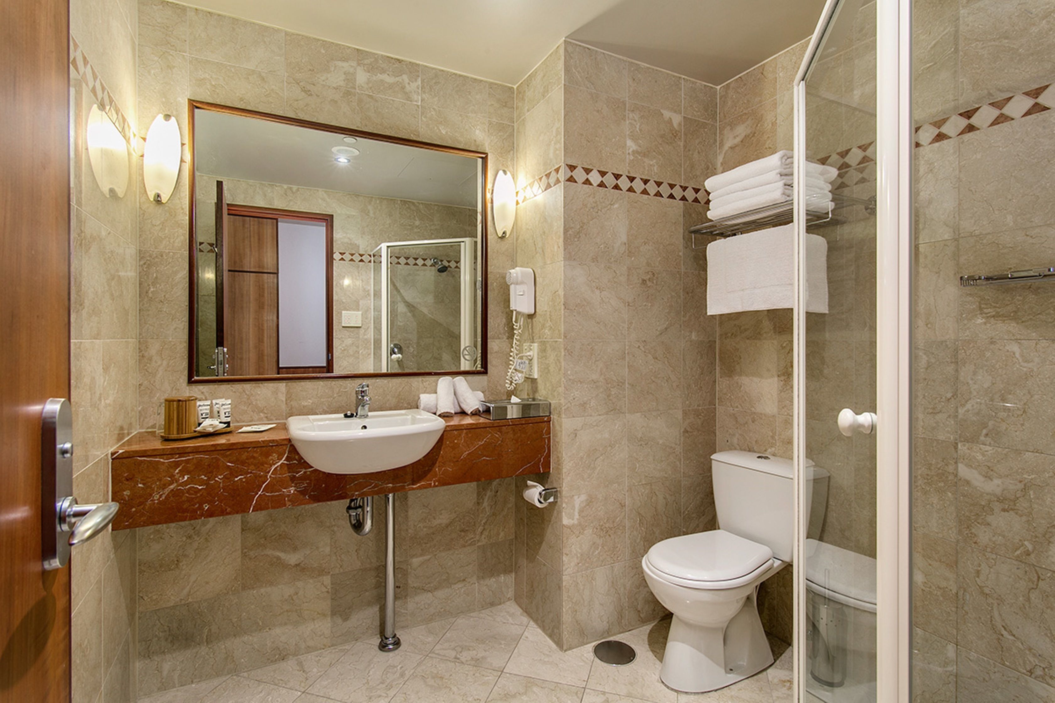 A bathroom with a marble sink, a toilet, and a glass-enclosed shower.