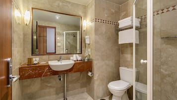 A bathroom with a marble sink, a toilet, and a glass-enclosed shower.