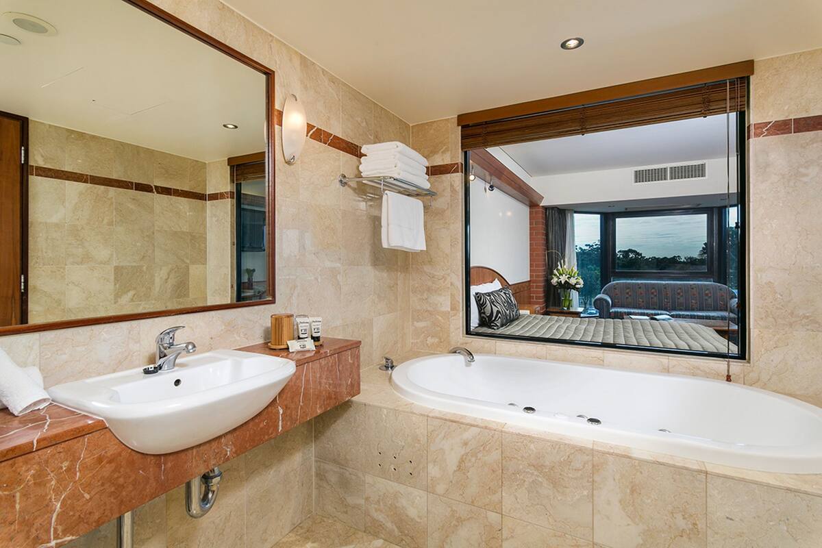 A bathroom with a sink, a bathtub, and a large mirror.