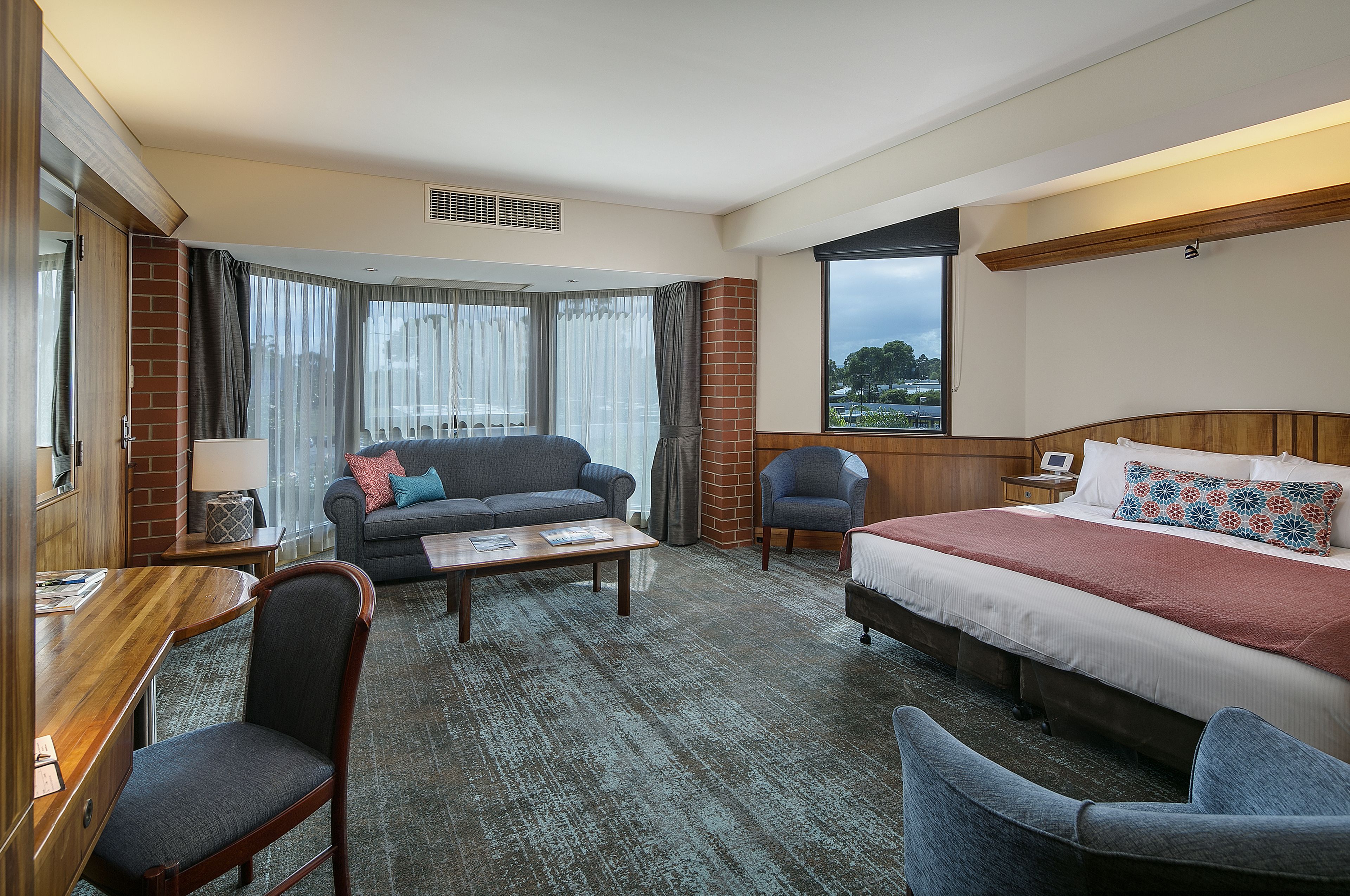 A hotel room with a bed, a sofa, a desk, and a chair.