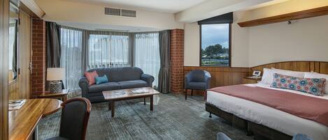 Une chambre d’hôtel avec un lit, un canapé, un bureau et une chaise.