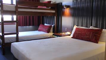 A hotel room with two bunk beds and a single bed, equipped with a telephone and a nightstand.