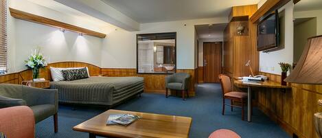 A hotel room with a bed, two sofas, a coffee table, a desk, and a TV.