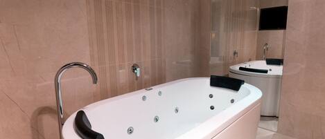 A modern bathroom with a freestanding bathtub, a vanity with a mirror, and a wall-mounted TV.