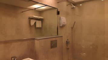A modern bathroom with a glass-enclosed shower, a sink with a soap dispenser, and a towel rack.