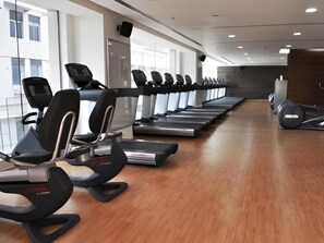 A gym with treadmills aligned along the walls, a wooden floor, and a weight bench area. - 24 Tech Hotel (Bengaluru)