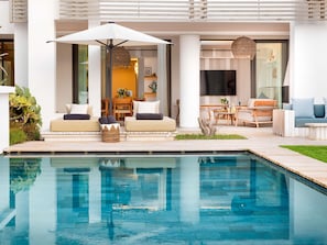 A modern outdoor living area with a pool, seating, and a dining setup.