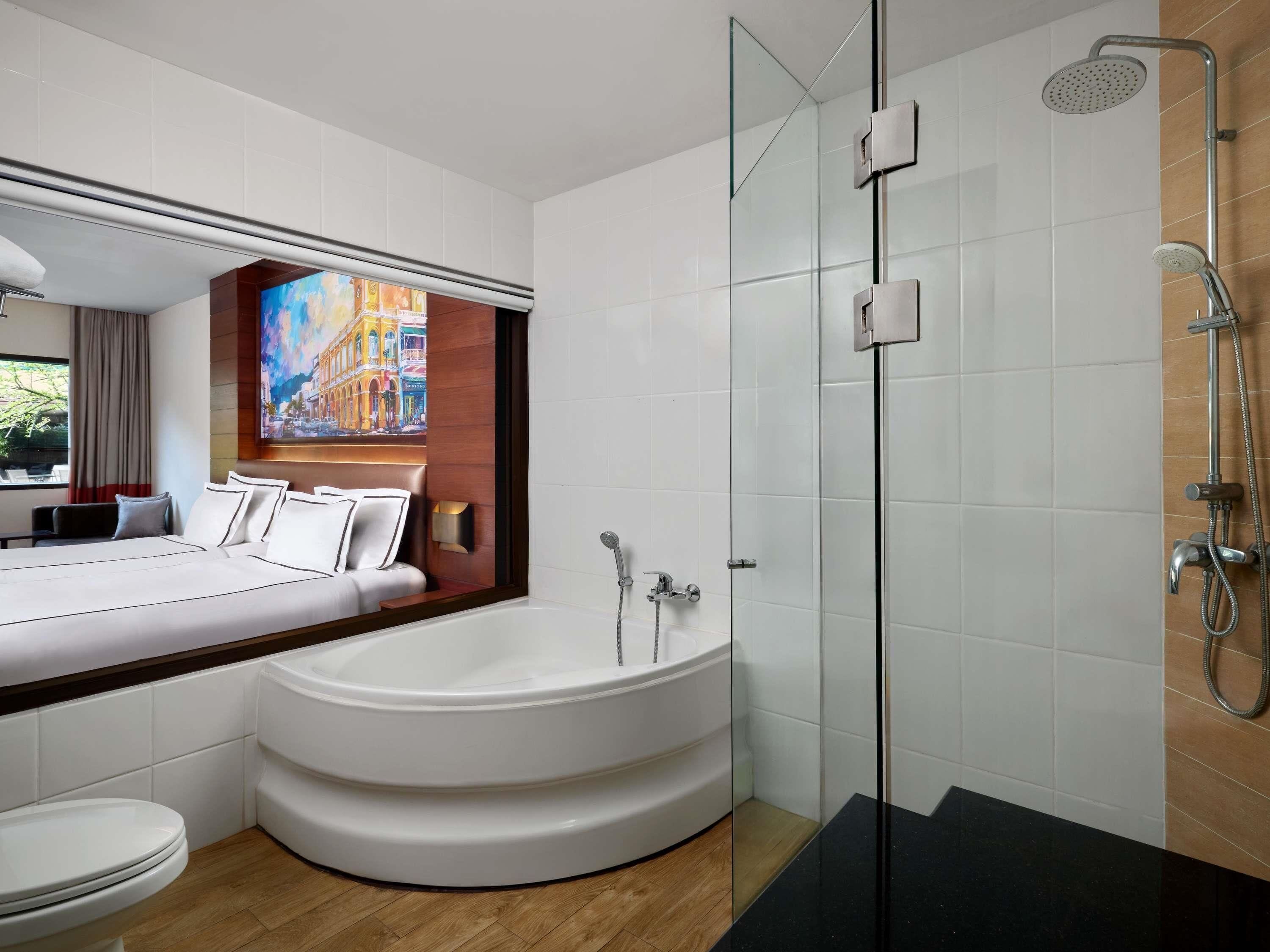 Un baño moderno con una bañera grande, una ducha con mampara de vidrio y un inodoro a la vista.