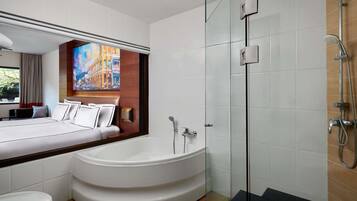 Une salle de bain moderne avec une grande baignoire, une douche à l’italienne et des toilettes apparentes.