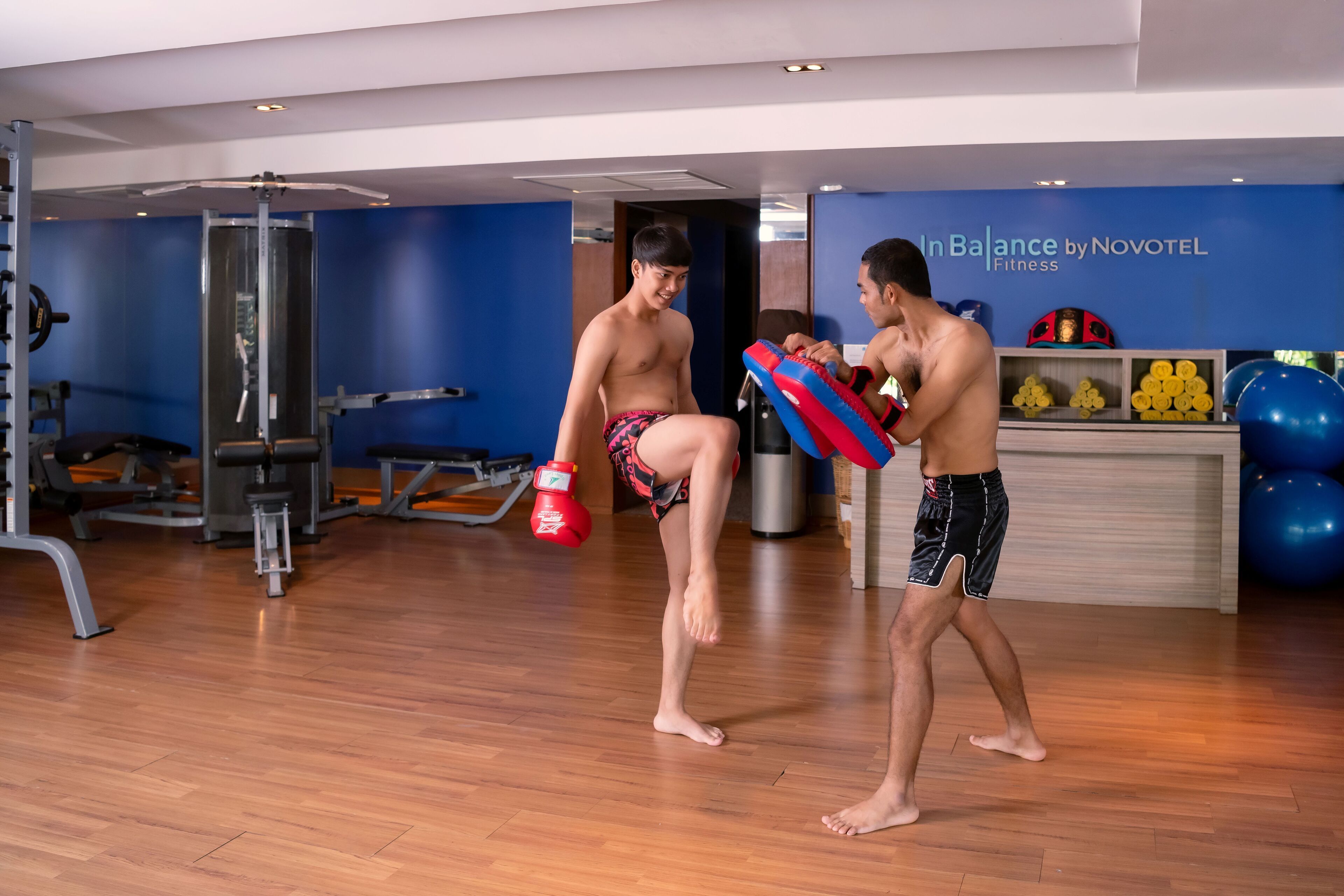 A gym with exercise equipment, a punching bag, and a wall with a fitness center sign.