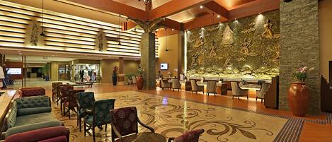 A spacious lobby with a reception desk, plush seating, and a decorative wall mural.