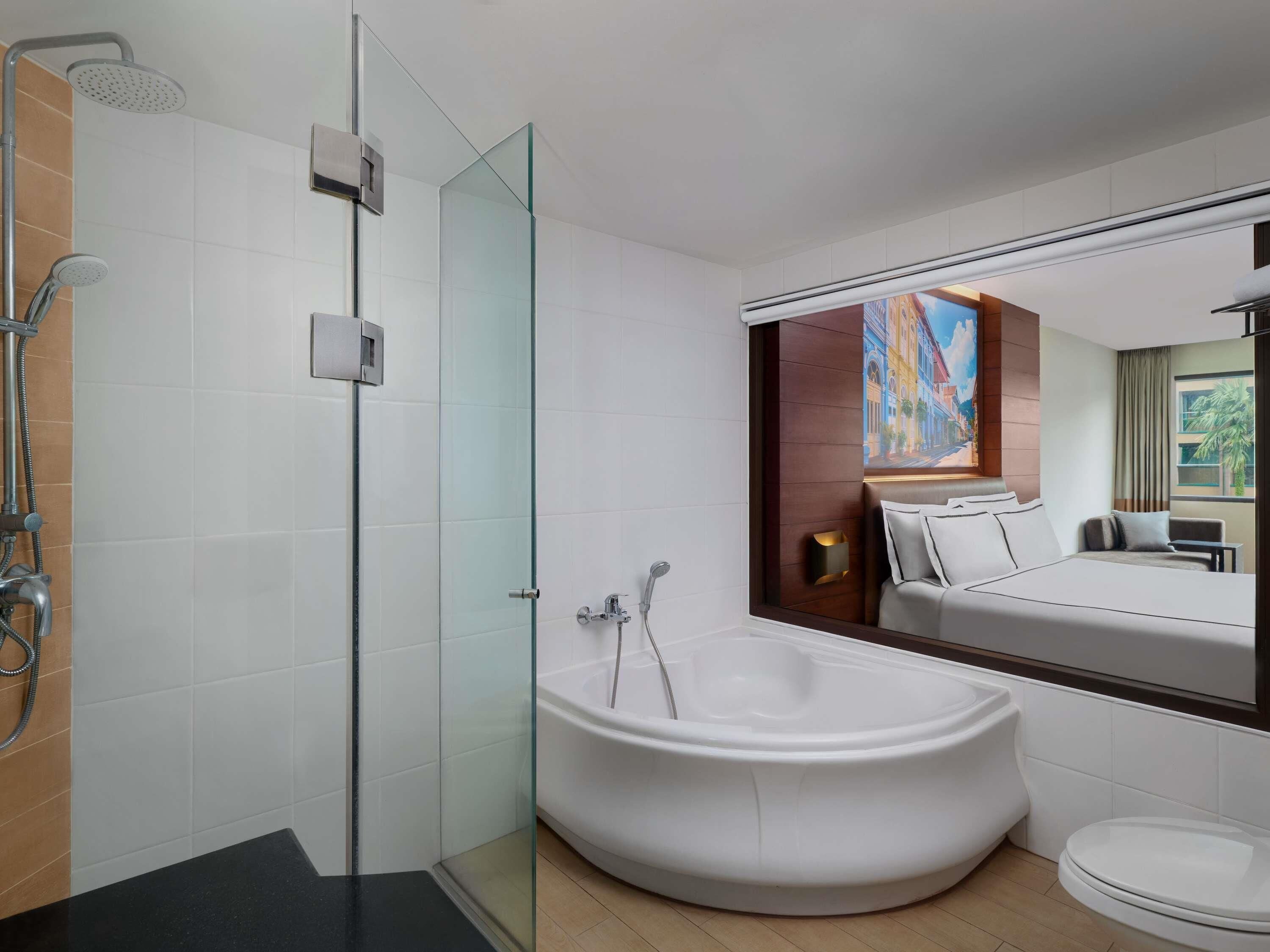 A modern bathroom with a glass shower enclosure, a freestanding bathtub, and a large mirror reflecting the room.