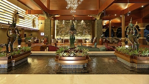 A lobby with a central fountain, seating areas, and a chandelier.