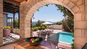 A patio with a table, chairs, and a view of a swimming pool. - Spilia Village Hotel & Villas (Platanias)