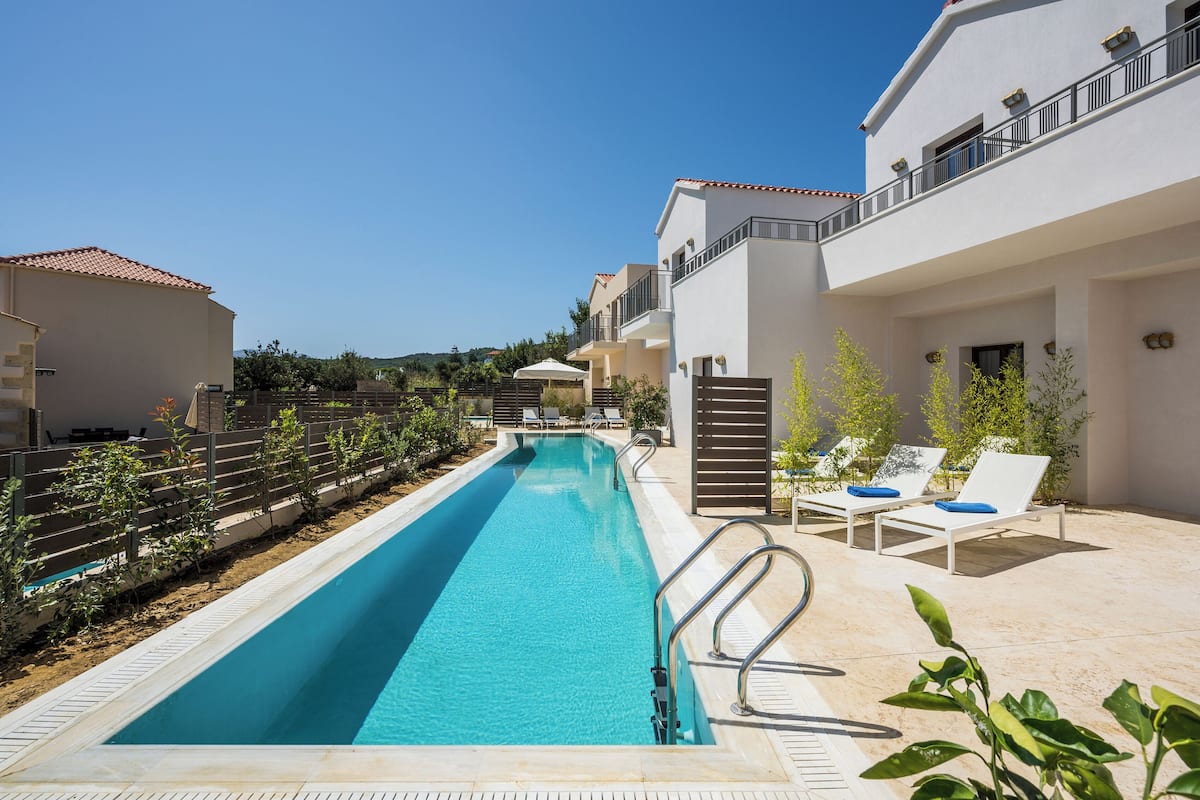 A swimming pool with lounge chairs and a clear sky.