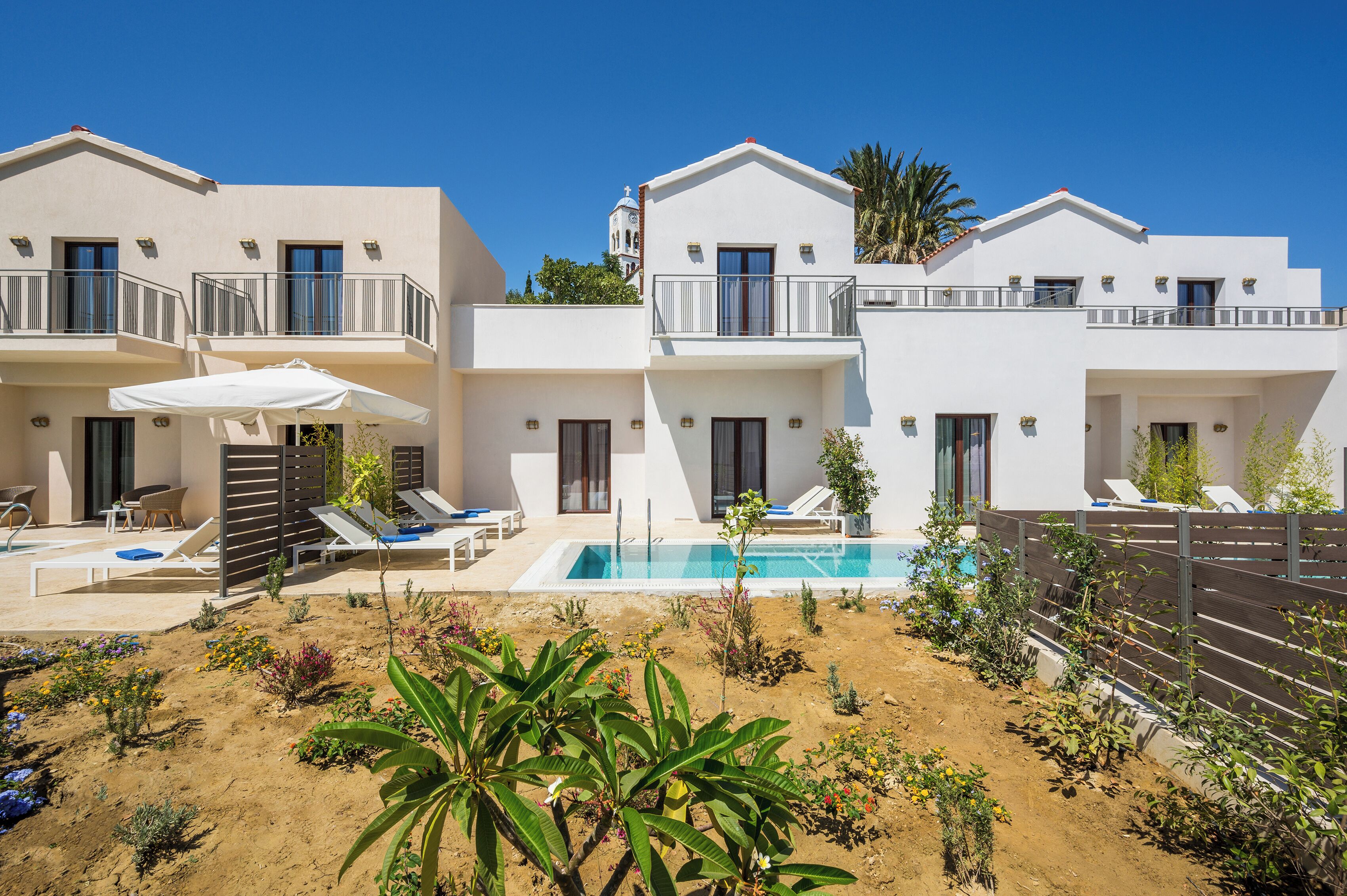 Un hôtel moderne doté d’une piscine, de chaises longues et d’un petit jardin.