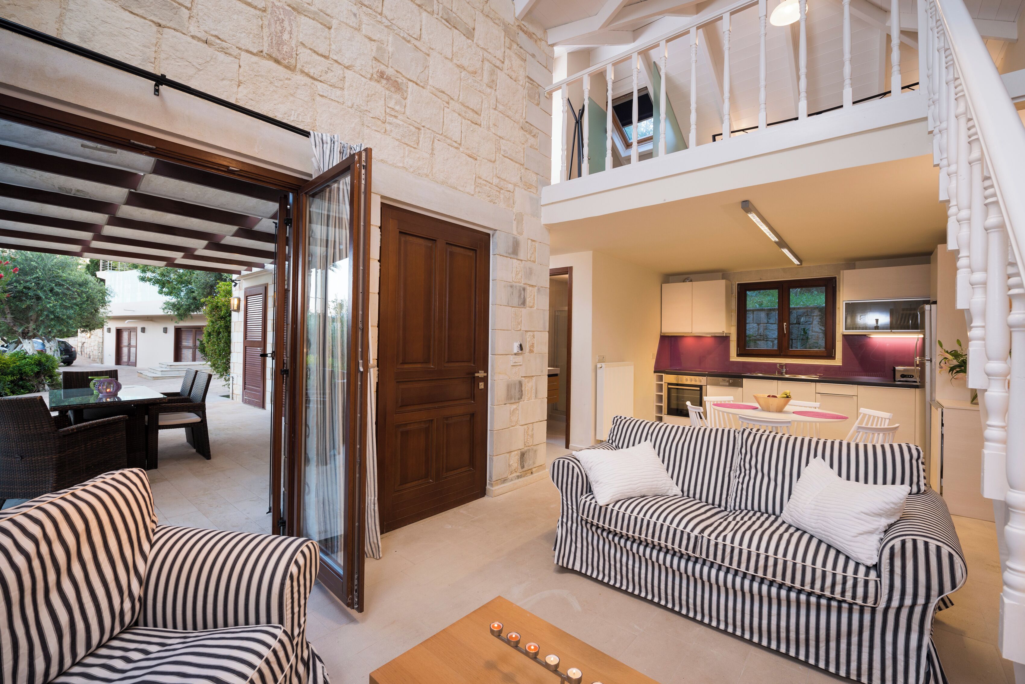 A spacious living area with a striped sofa, a wooden coffee table, and a dining area with a table and chairs.
