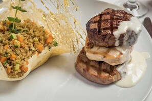 Un plato con un bistec a la parrilla y una guarnición de cuscús con verduras.