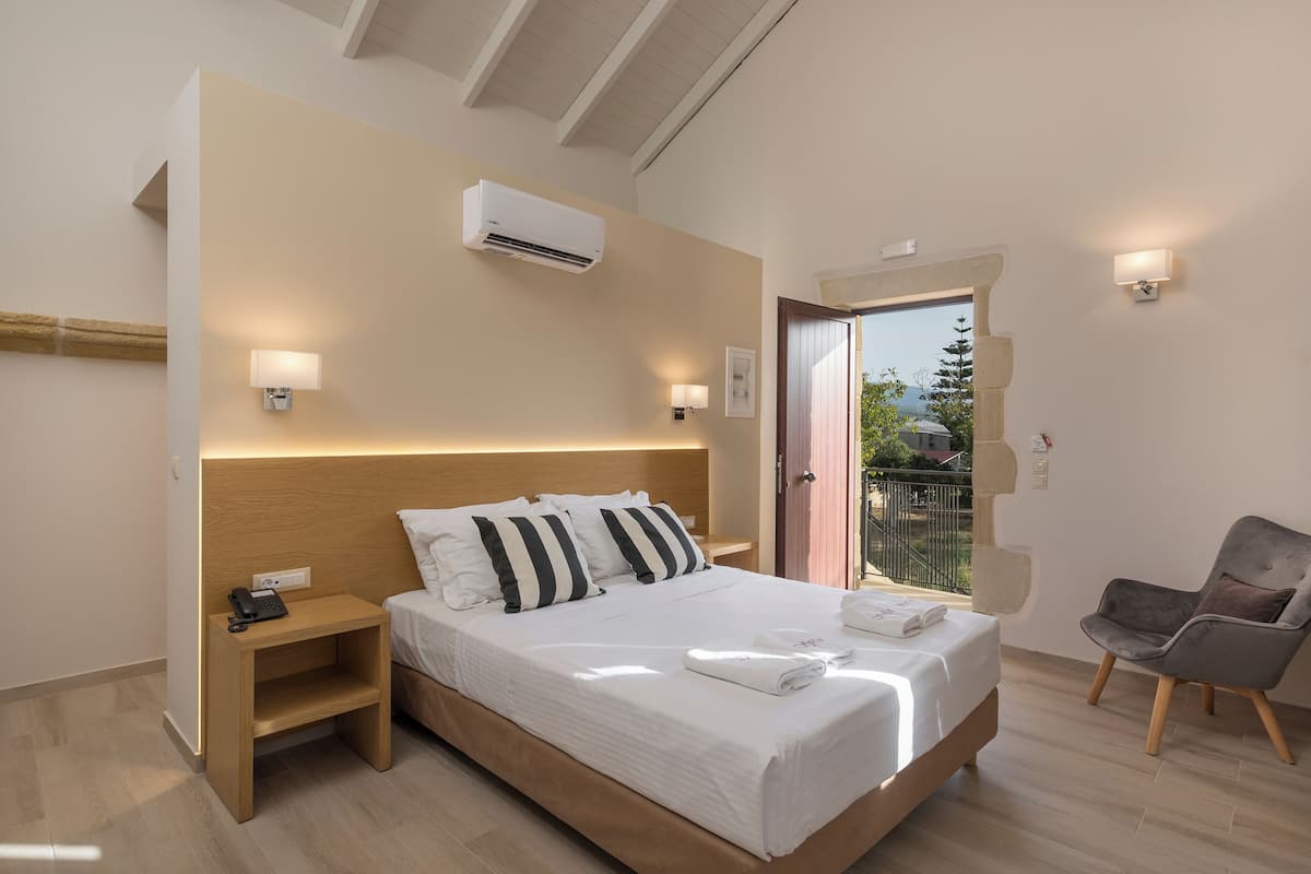A modern hotel room with a large bed, bedside lamps, a small table, and a chair.