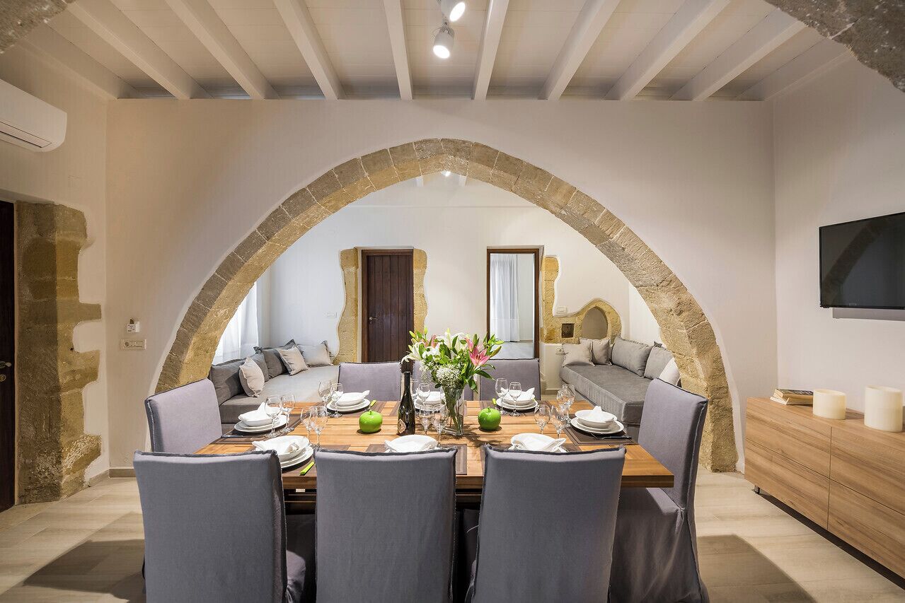 A dining area with a stone arch, a sofa, and a TV mounted on the wall.