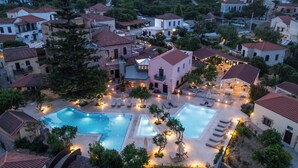 A residential area with a swimming pool surrounded by lounge chairs and umbrellas, with houses in the background. - Spilia Village Hotel & Villas (Platanias)