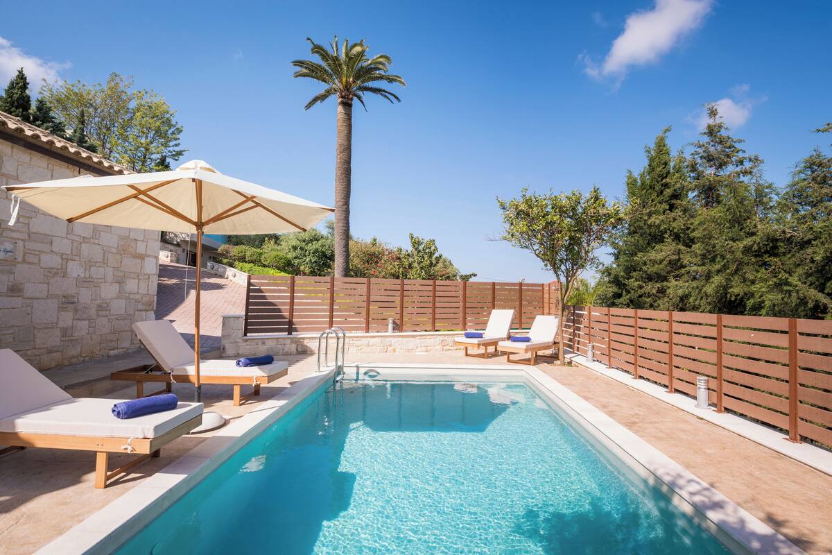 A rectangular swimming pool with lounge chairs and an umbrella.