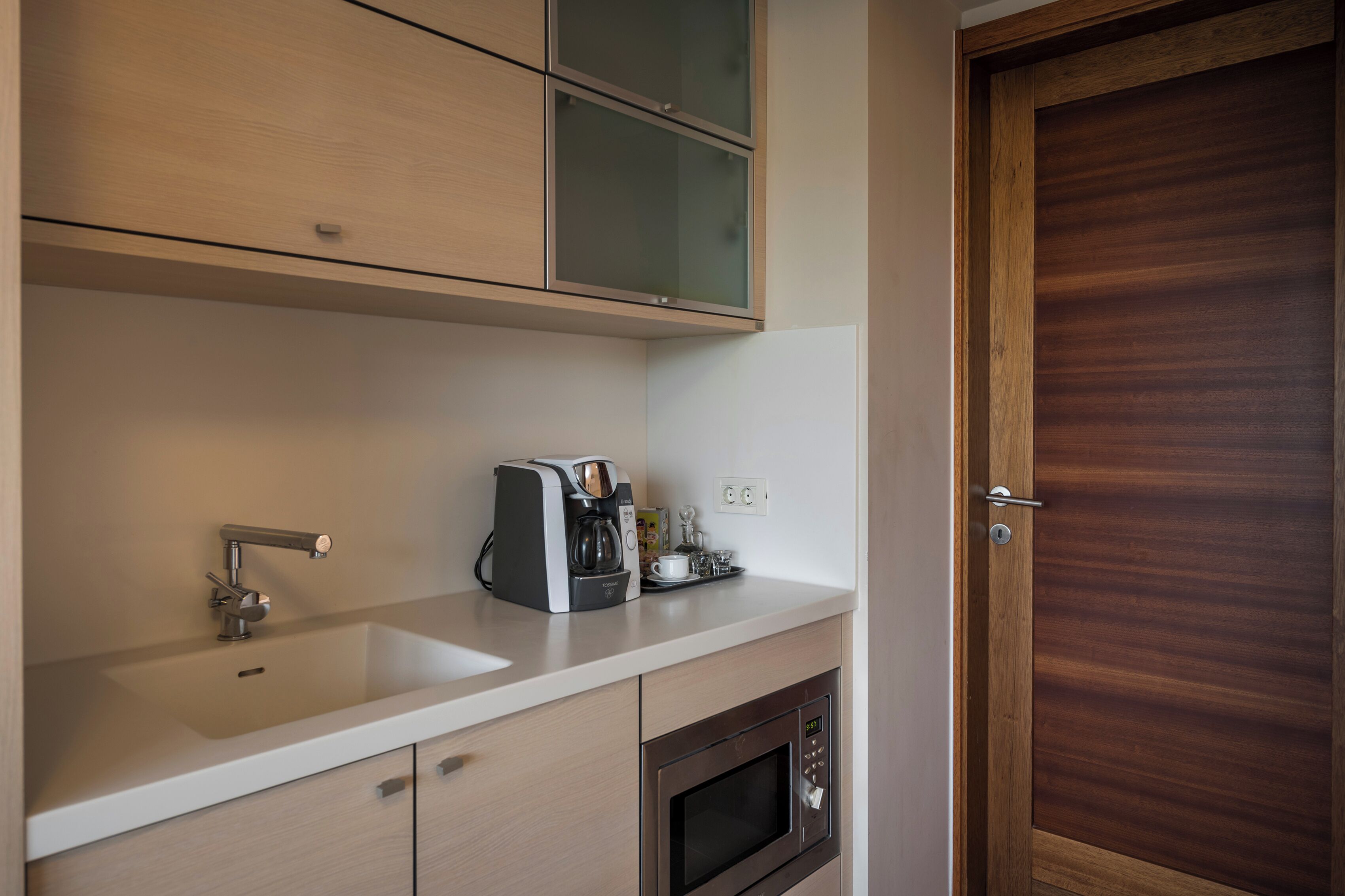 A kitchenette with a built-in oven, a coffee maker, and a sink.