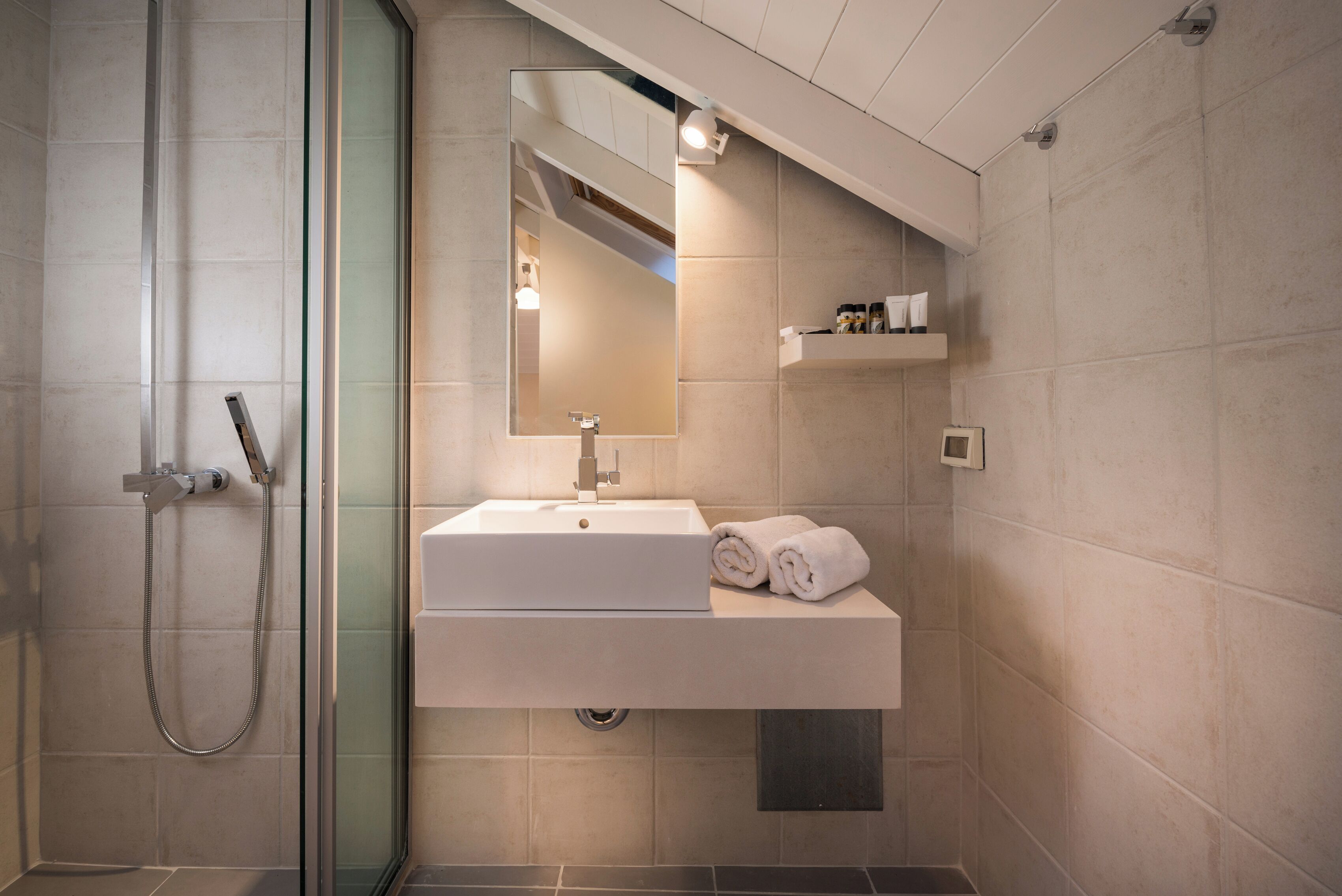 A modern bathroom with a glass-enclosed shower, a white sink, and a mirror above it.