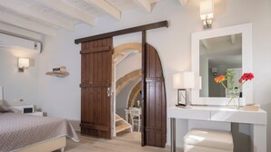 A bedroom with a bed, a desk, a mirror, and a staircase leading to an upper level. - Spilia Village Hotel & Villas (Platanias)
