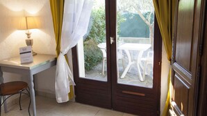 A room with a wooden door, a small table with a lamp, and a chair. - Motel Capsol (Mandelieu-La-Napoule)