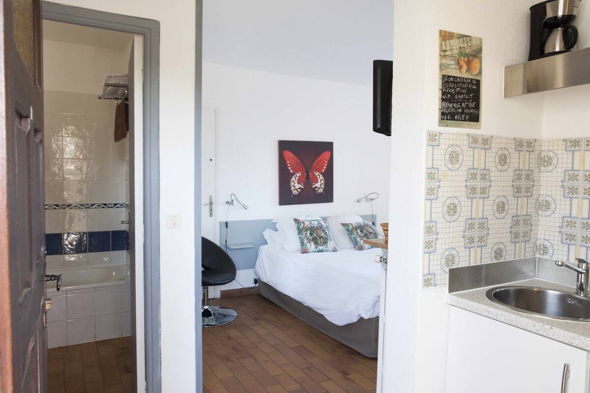 Une chambre à coucher avec un lit, une chaise et une salle de bain comprenant une baignoire et un lavabo.