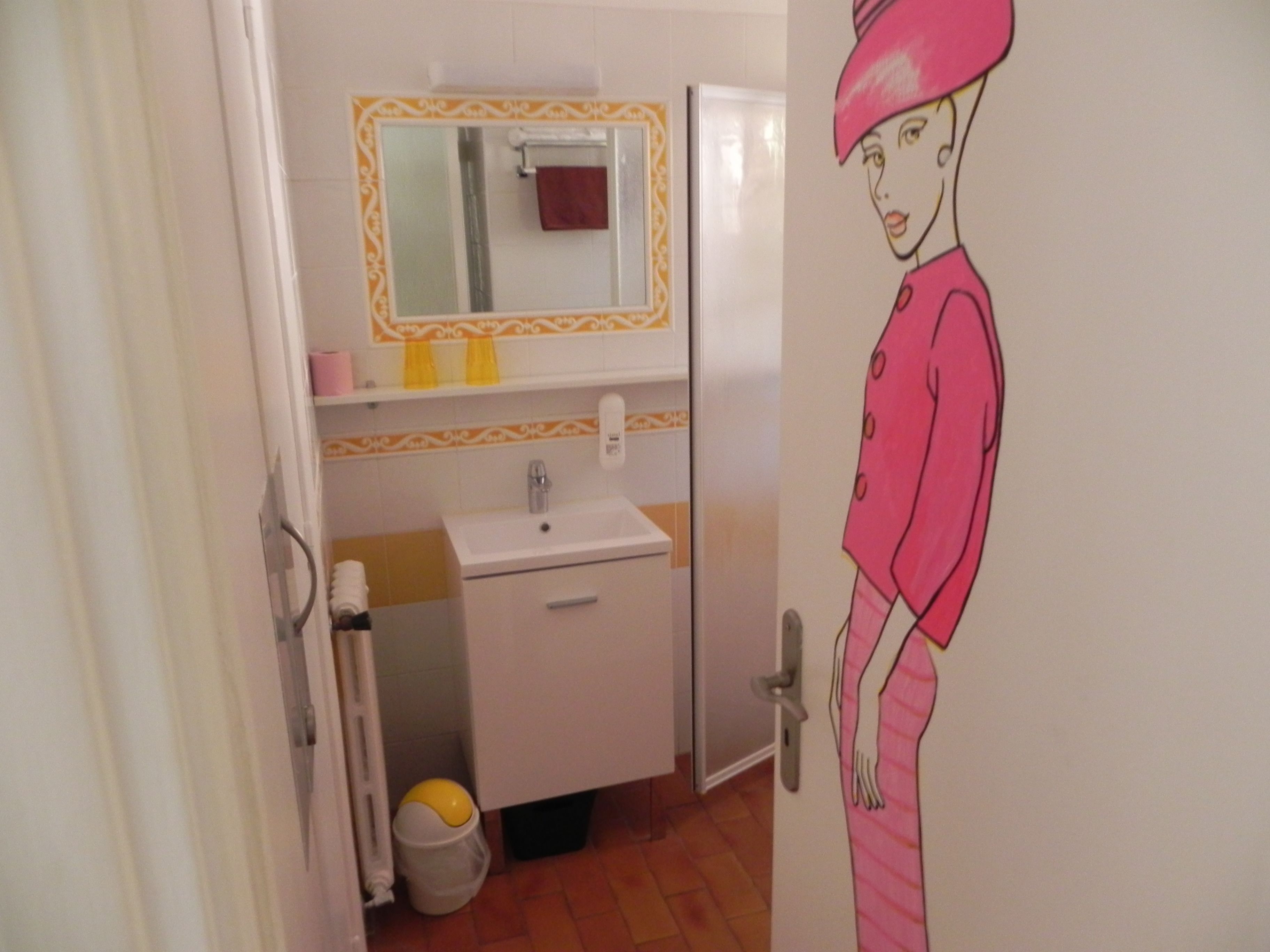Een badkamer met een wastafel, spiegel en een deur met een tekenfilmfiguur.