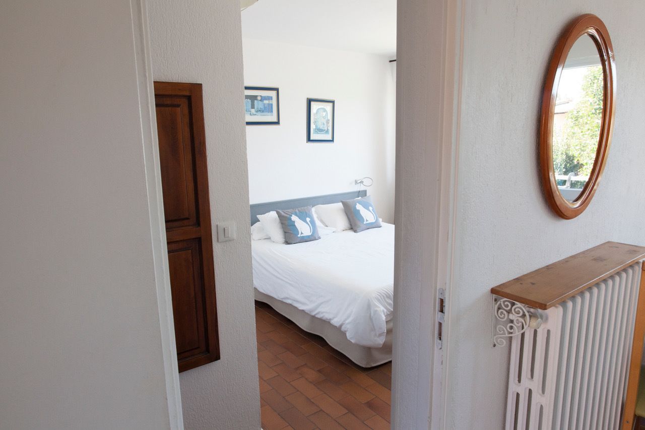 A bedroom with a bed, a wooden door, a radiator, and a mirror on the wall.