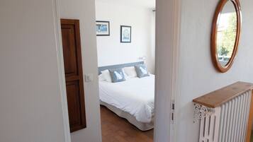 A bedroom with a bed, a wooden door, a radiator, and a mirror on the wall.
