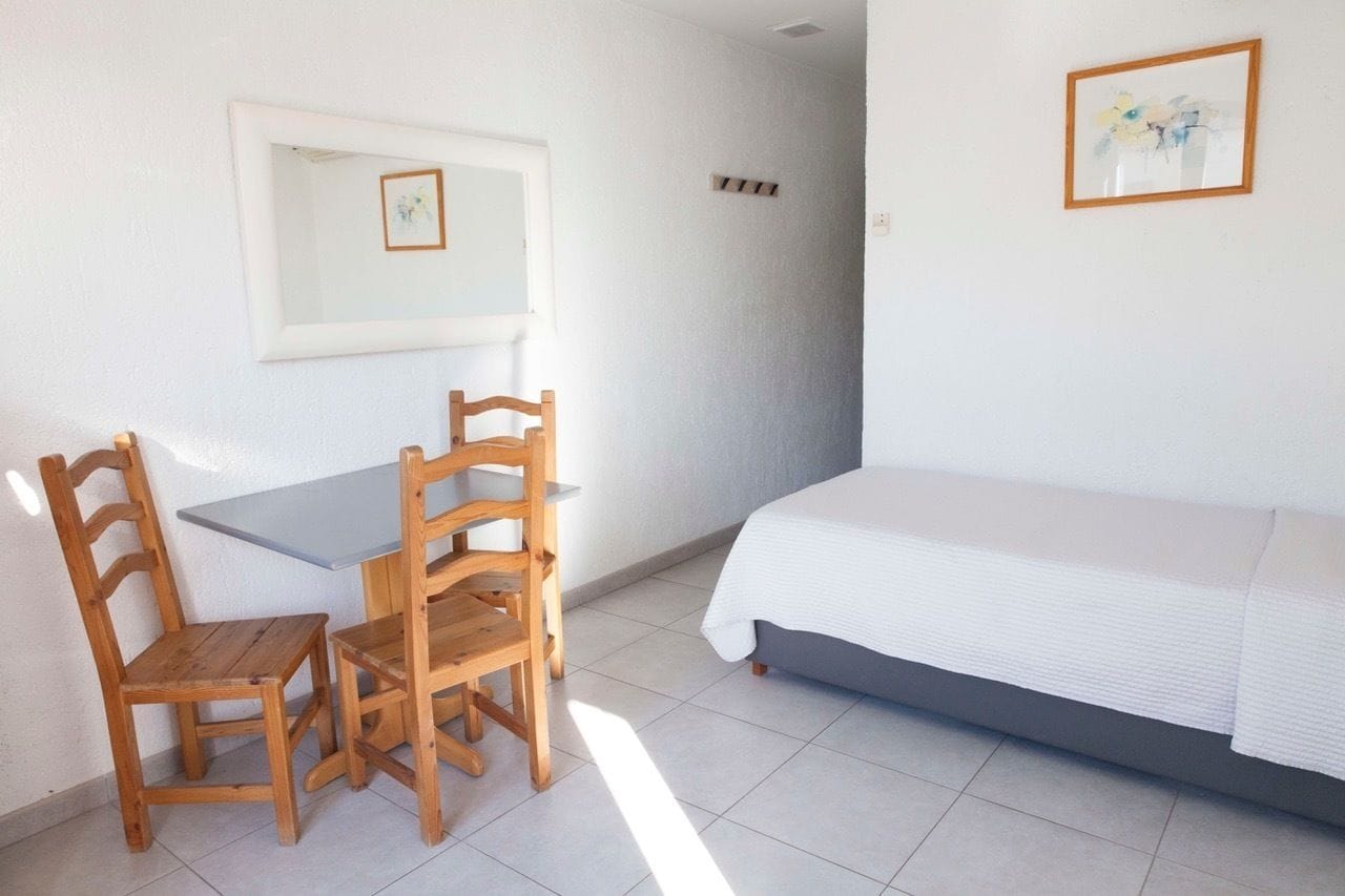 A room with a bed, a table, and two chairs.