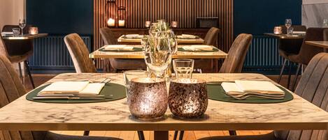 Un ristorante con tavoli in marmo, sottopiatti verdi e centrotavola illuminati da candele.